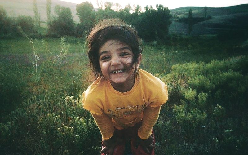 A child laughing outdoors in a sunlit field.
